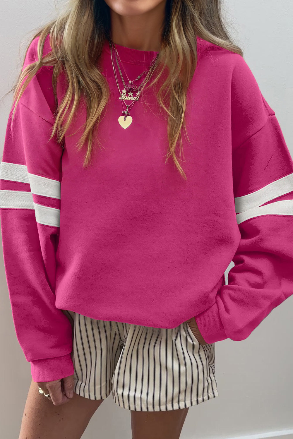 Rosarotes Oversize-Sweatshirt mit Collegestreifen und überschnittenen Schultern.